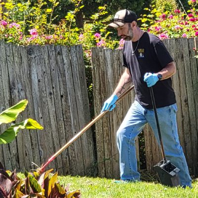 A man is actively raking leaves in a yard, working to maintain a clean and organized outdoor environment A man is actively raking leaves in a yard, working to maintain a clean and organized outdoor environment